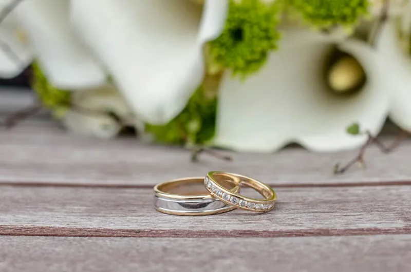 Alianzas de boda de oro bicolor, una de ellas con diamantes, sobre madera