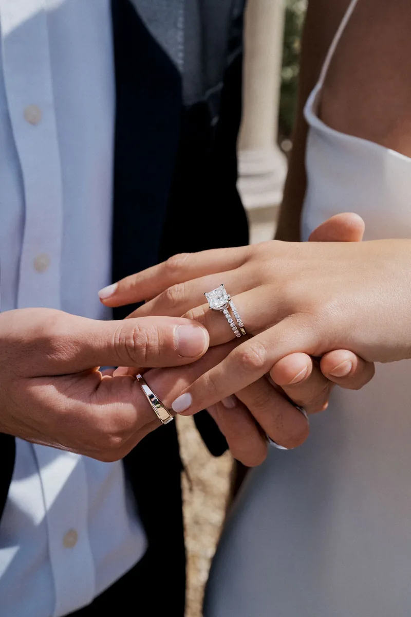 Anillo de compromiso con diamante talla princesa y alianza pavé de diamantes junto a alianza de novio