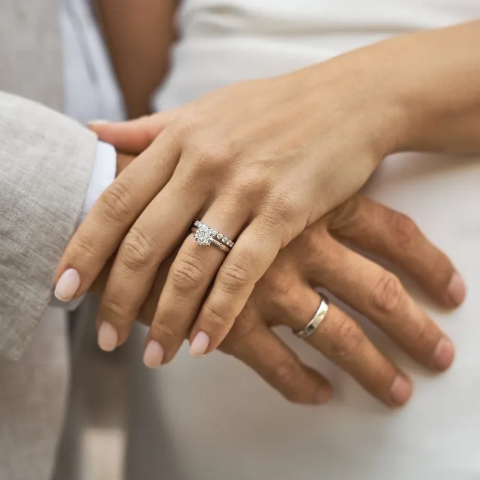 Pareja con anillo de compromiso solitario, alianza de diamantes y alianza de boda de oro blanco