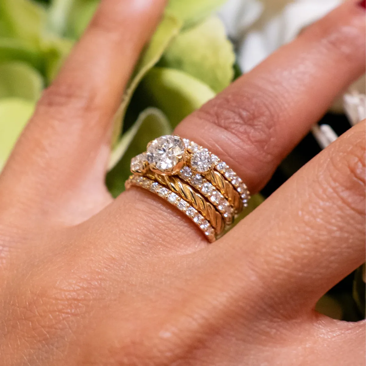 Anillo de compromiso de tres diamantes en oro amarillo con alianzas trenzadas y de diamantes