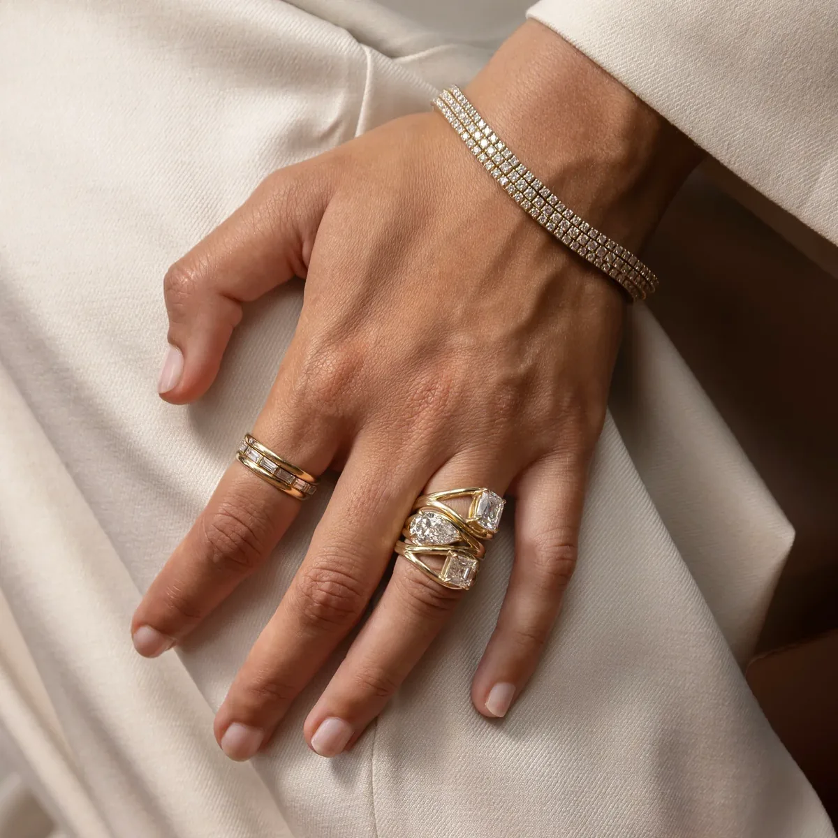 Anillos de compromiso de oro amarillo con diamantes talla pera y esmeralda junto a pulsera rivière