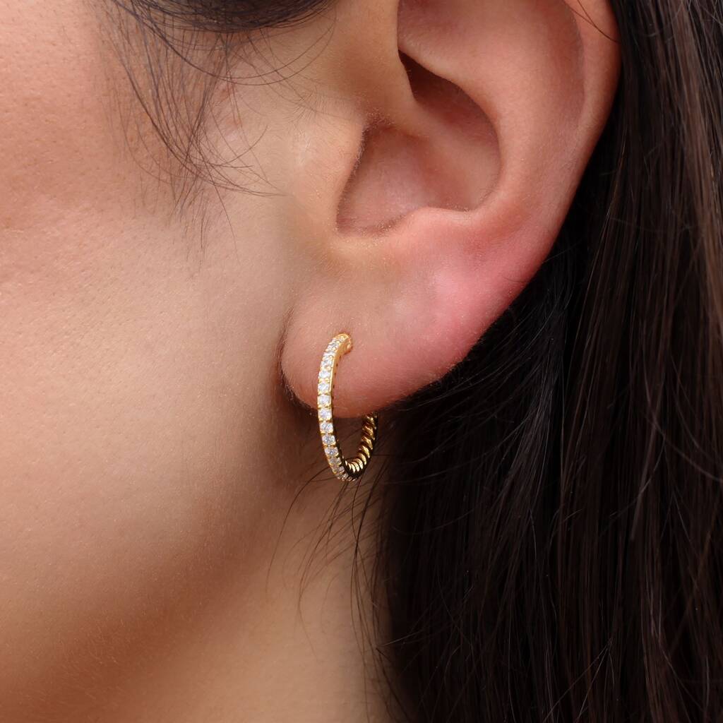 Aro fino de oro amarillo puesto en la oreja