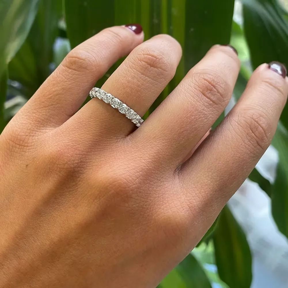 Media alianza de diamantes en oro blanco en la mano