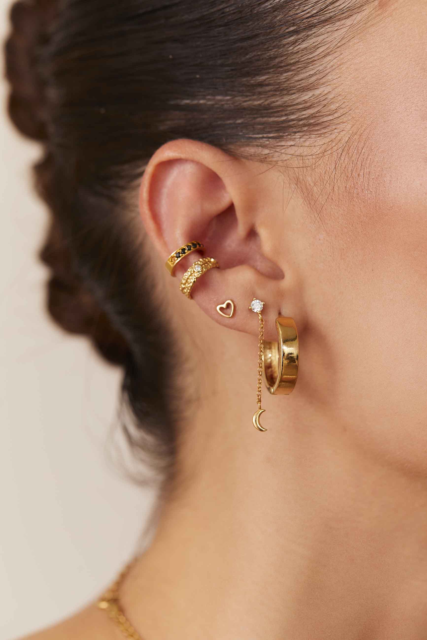 Aro pequeño de oro con colgante puesto en la oreja