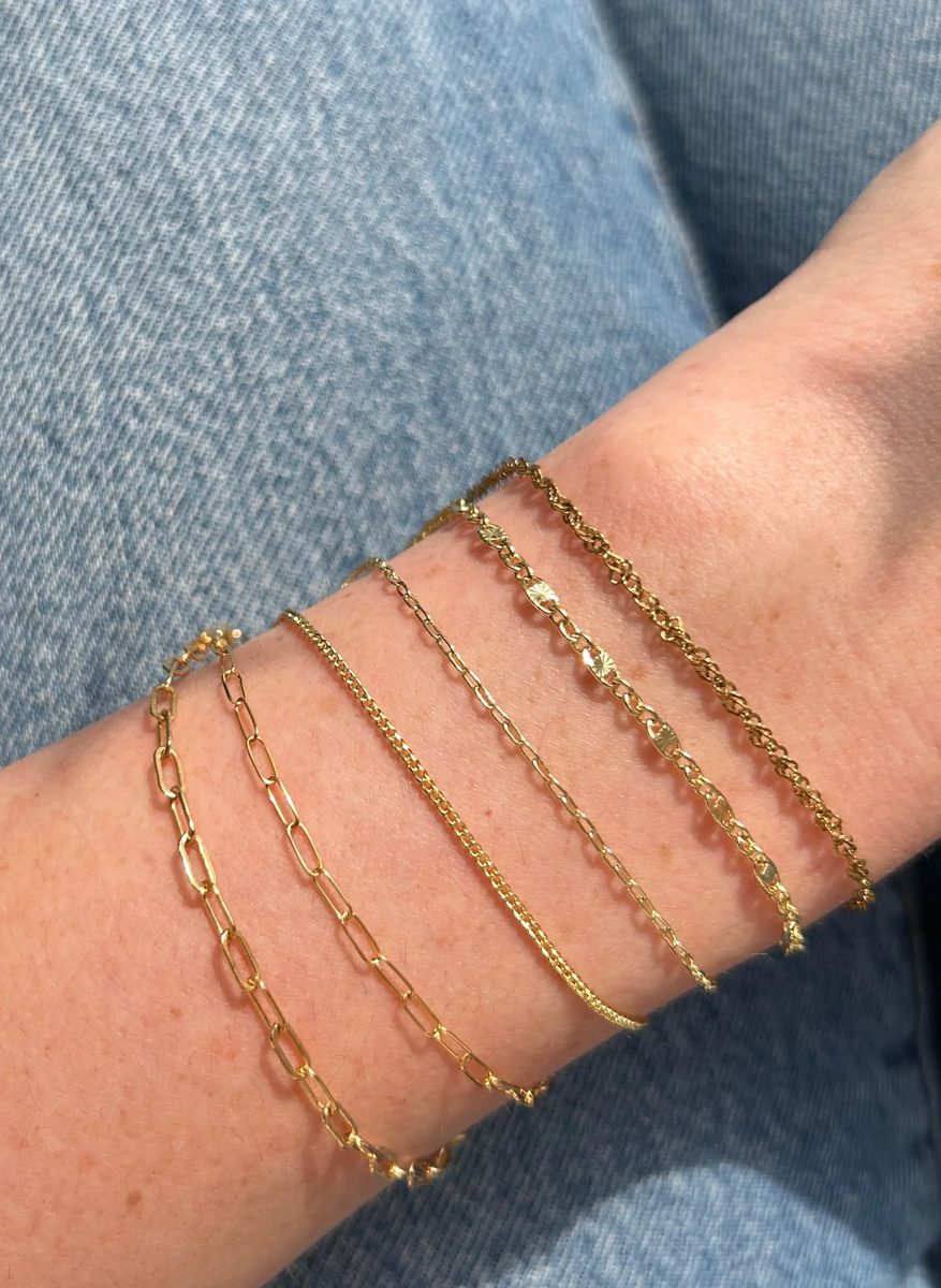 Varias pulseras de oro finas de mujer combinadas en la muñeca
