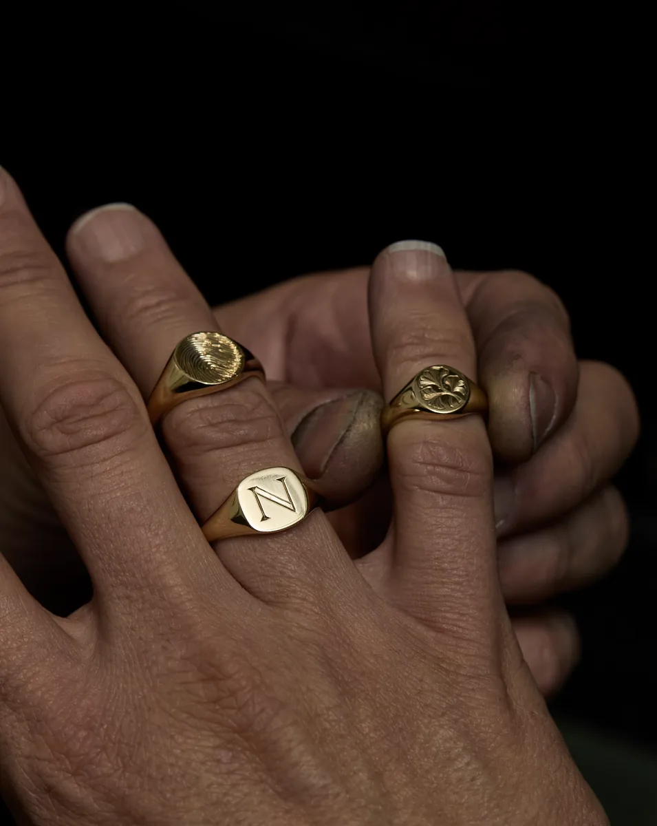 Tres sellos de oro grabados con una inicial, una huella y una hoja